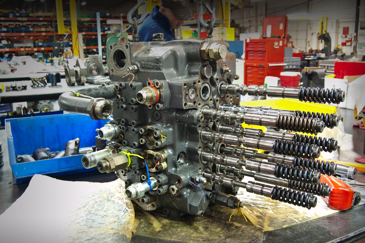 Disassembled grey main control valve with spools extended out of sections in for valve repair.