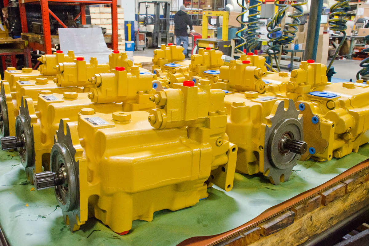 Yellow painted Hydraulex Reman Vickers hydraulic pumps lined up on bench awaiting packaging and shipping.